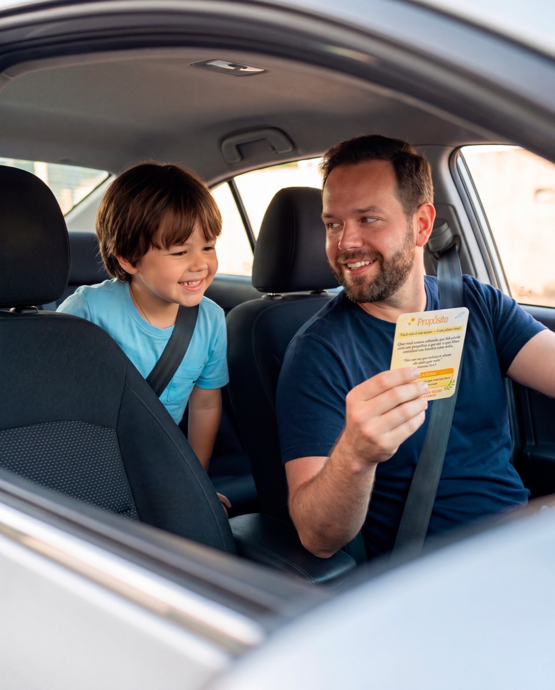 Pai mostrando card da Caixinha do Céu para o filho no carro